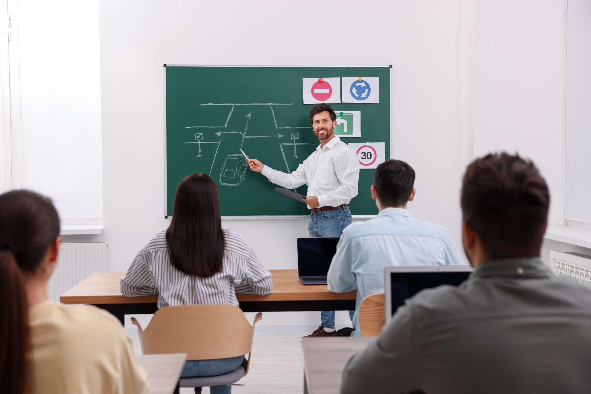 Teacher explaining traffic rules to audience during lesson in driving school